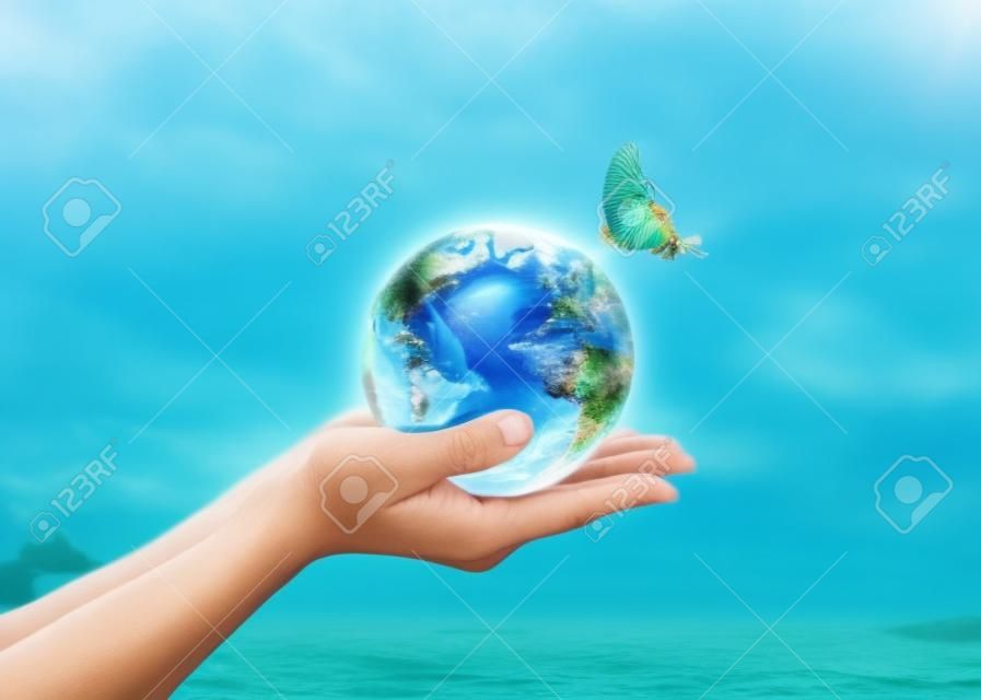 Werelddag van de oceaan, het redden van water campagne, duurzame ecologische ecosystemen concept met groene aarde op de handen van de vrouw op blauwe zee achtergrond