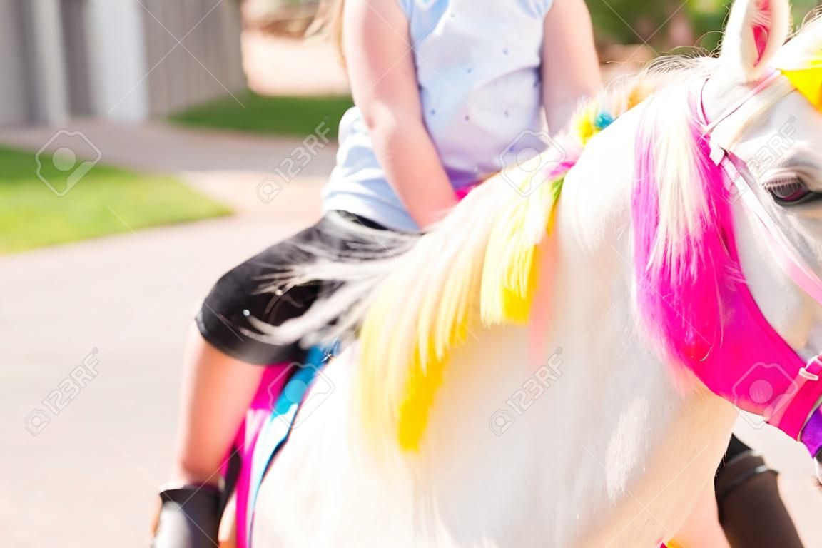 Niña montando un unicornio en la fiesta de cumpleaños de la niña.
