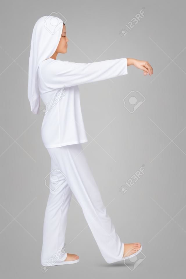Donna di sonnambulismo isolata su sfondo bianco. Vista di profilo di giovane donna a piedi nel suoi dorme in pigiama, con le braccia alzate. Immagine full length