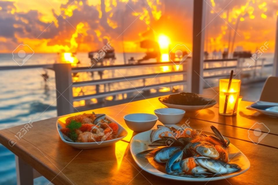 dining table with seafoods with golden light on sunset at seafoods restaurant nearby the beach