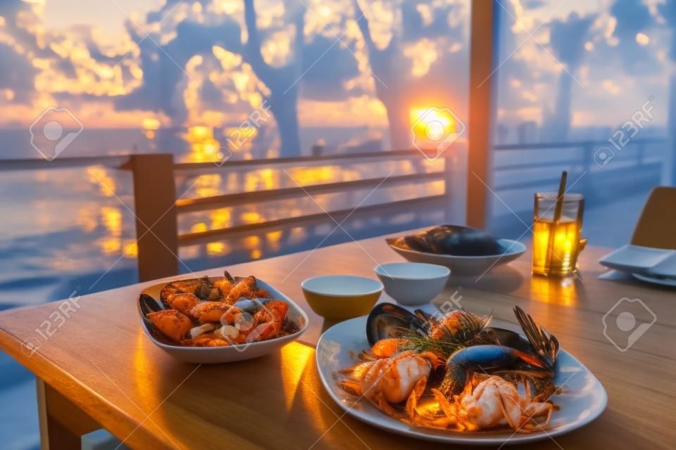 dining table with seafoods with golden light on sunset at seafoods restaurant nearby the beach