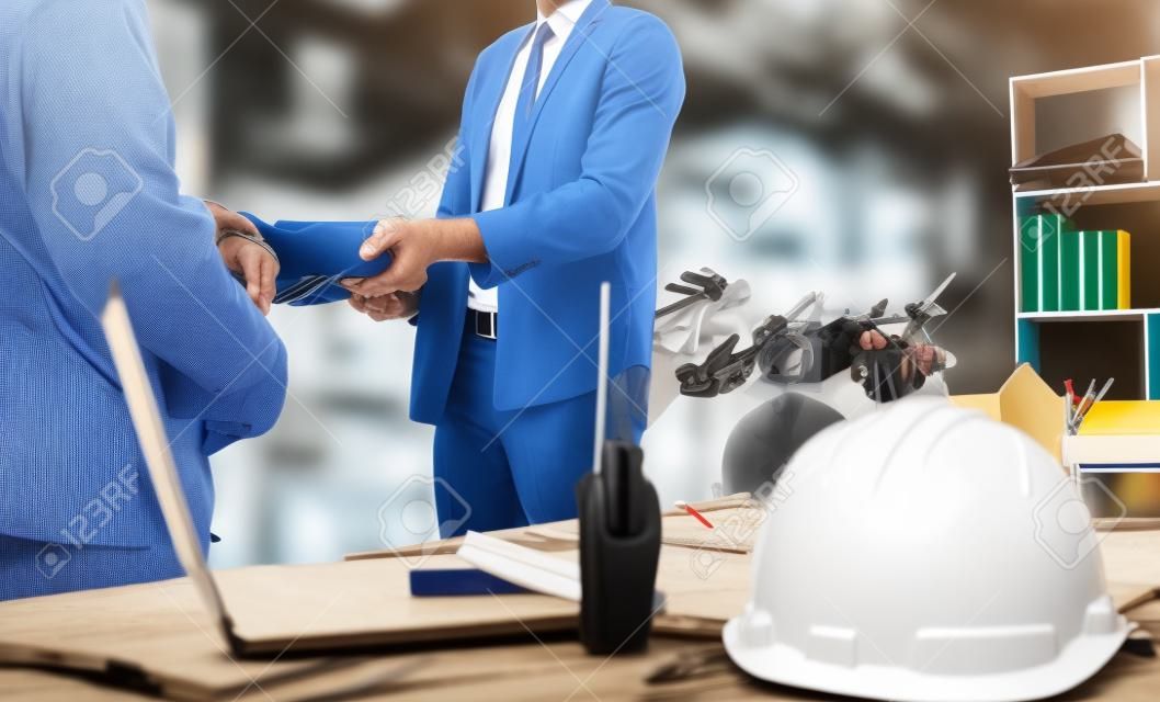 Two business man construction site engineer. Engineering objects on workplace with partners interacting on background