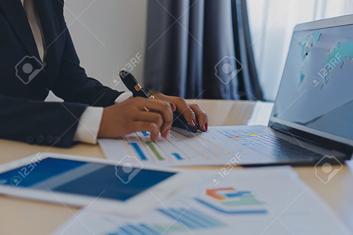 Feche a mulher de negócios usando calculadora e laptop para fazer finanças matemáticas em estatísticas de contabilidade fiscal de mesa de madeira e conceito de pesquisa analítica