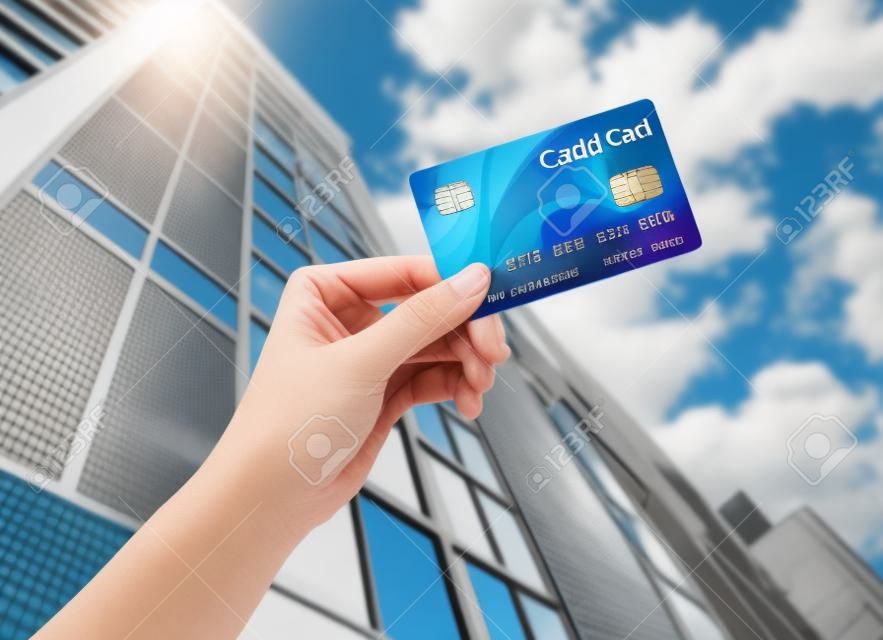 Рука кредитной карты против builind и неба