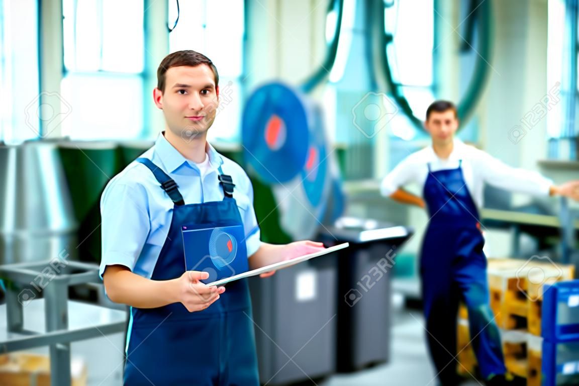 jonge baas met werknemer op de achtergrond in zijn fabriek