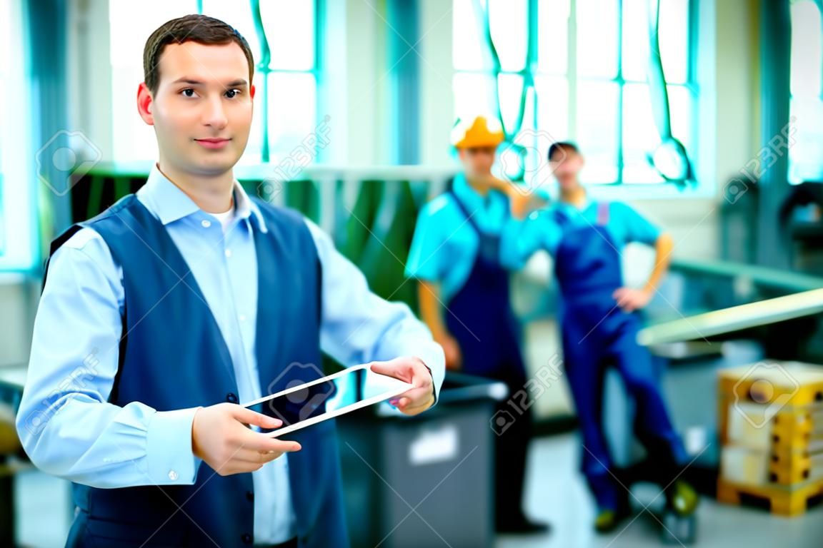 jonge baas met werknemer op de achtergrond in zijn fabriek