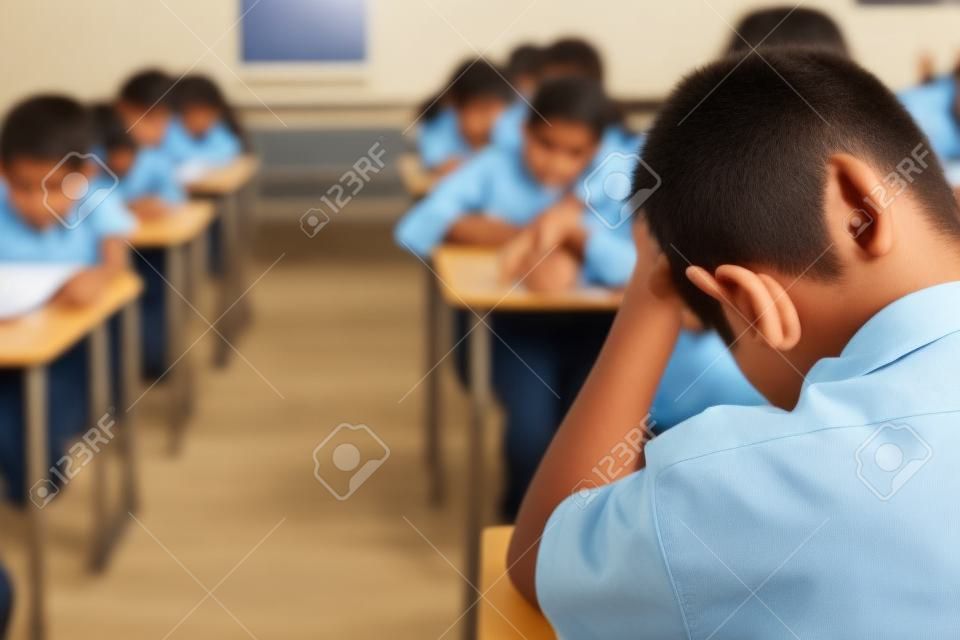 Alunos fazendo exercícios de folhas de respostas de exames em sala de aula da escola com estresse.