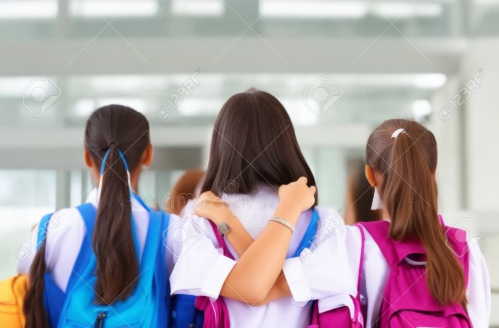 Konzept der besten Freunde, Gruppe von Studentenmädchen stehen umarmt und denken in der Schule