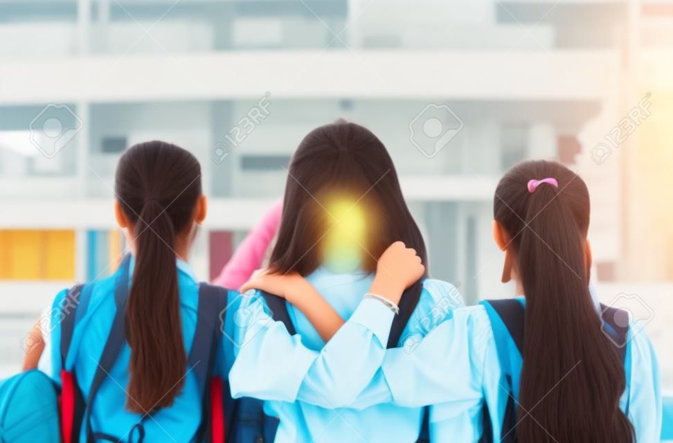 Konzept der besten Freunde, Gruppe von Studentenmädchen stehen umarmt und denken in der Schule