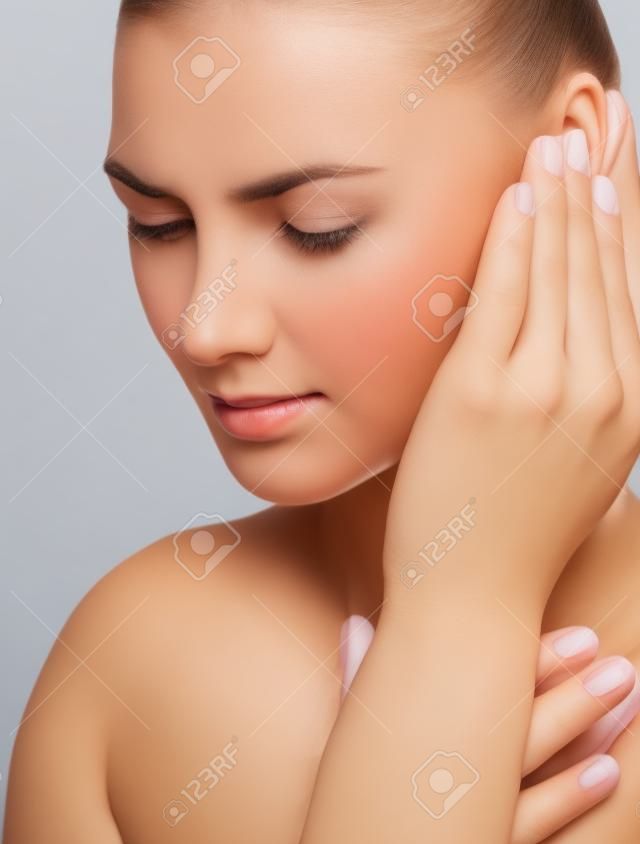 一位耳朵疼痛的年轻女子手牵着手，隔离在白色背景上。
