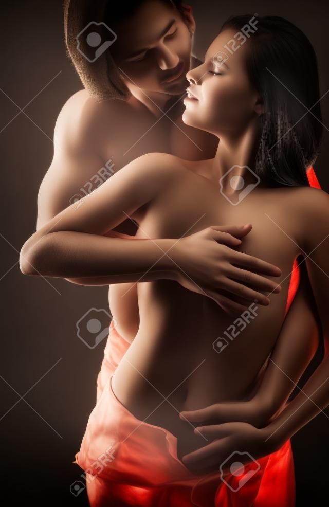 Young beautiful loving couple is embracing on a dark background