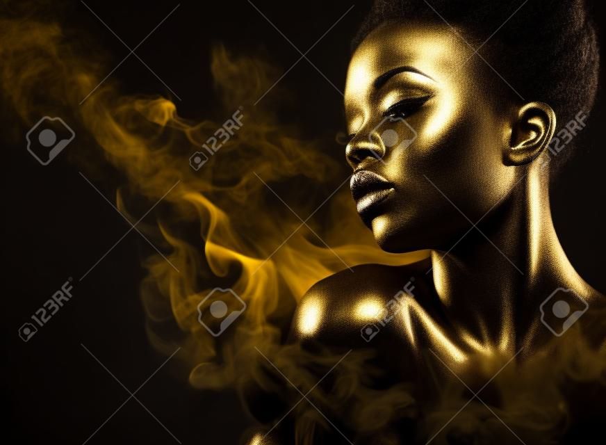 Jeune femme afro-américaine avec maquillage argent et or et art corporel sur fond noir avec de la fumée