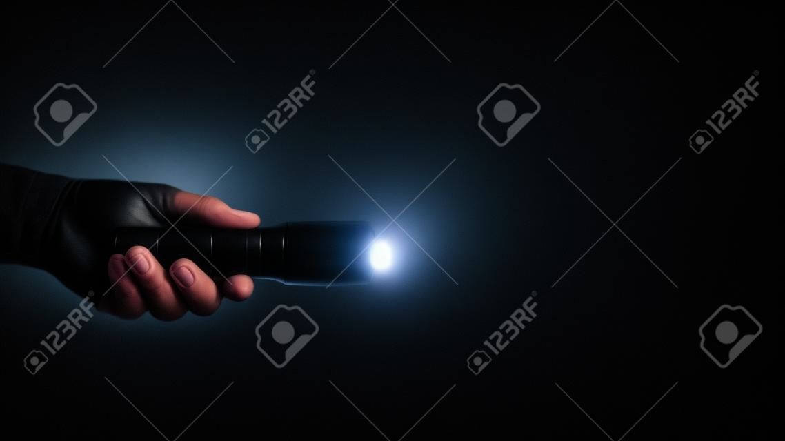 흰색 광선을 포함하여 검은 배경에 인간의 손에 검은 손전등.