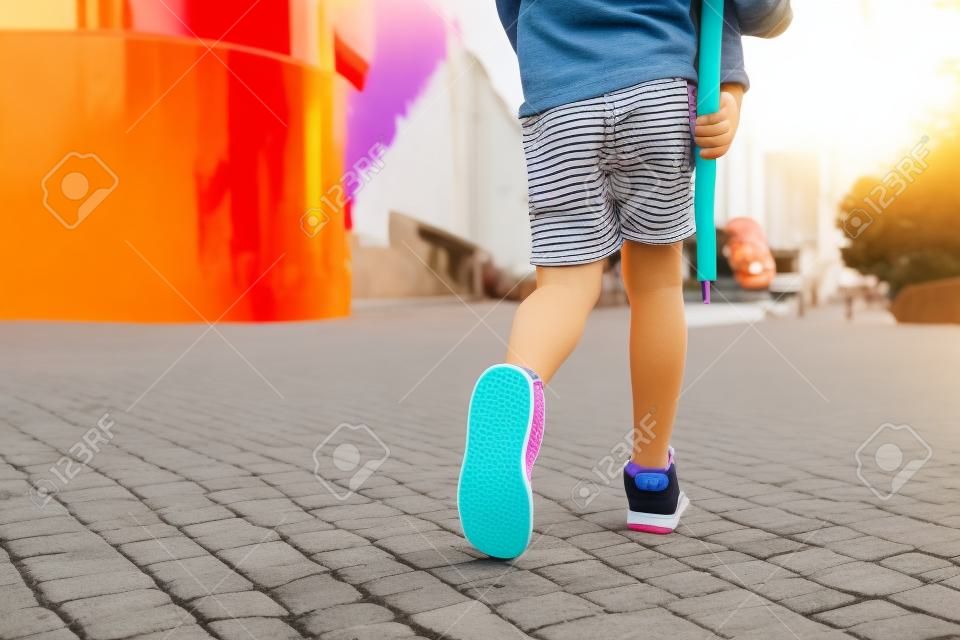 BOY legs in bright clothes walking with PENNY BOARD in the hands