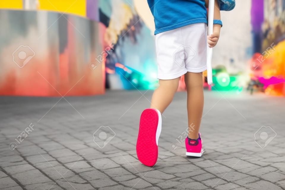 BOY legs in bright clothes walking with PENNY BOARD in the hands