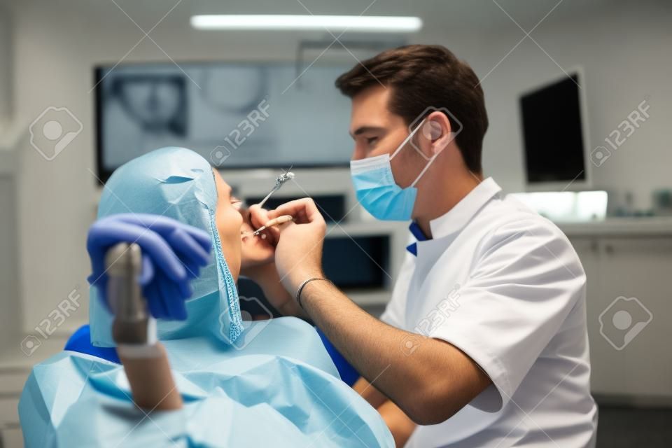 Caucasian male dentist examining young woman patients teeth at dental clinic. Doctor probing teeth with dental instrument using an explorer look for cavities treatment and checking problems