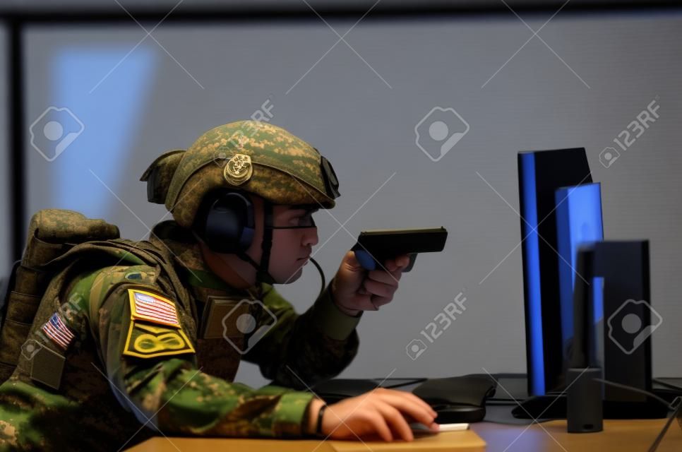 un militaire en uniforme assis devant un ordinateur mène une cyberguerre