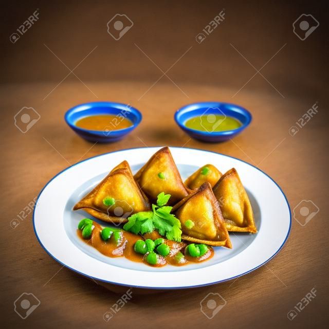 Samosa : a fried baked with spiced, potatoes, onion, peas and dipping sauce and pickle.