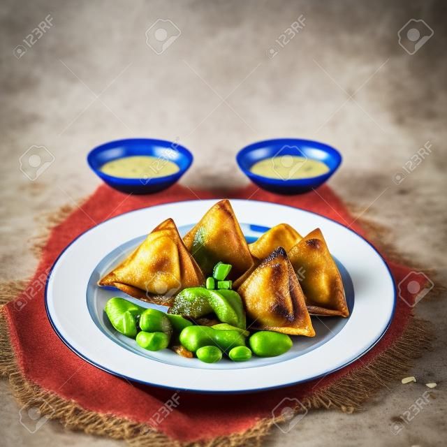 Samosa : a fried baked with spiced, potatoes, onion, peas and dipping sauce and pickle.