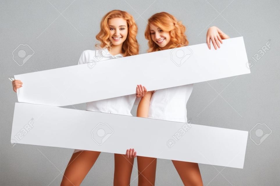 Belle giovani due donne tiene scheda bianca vuota