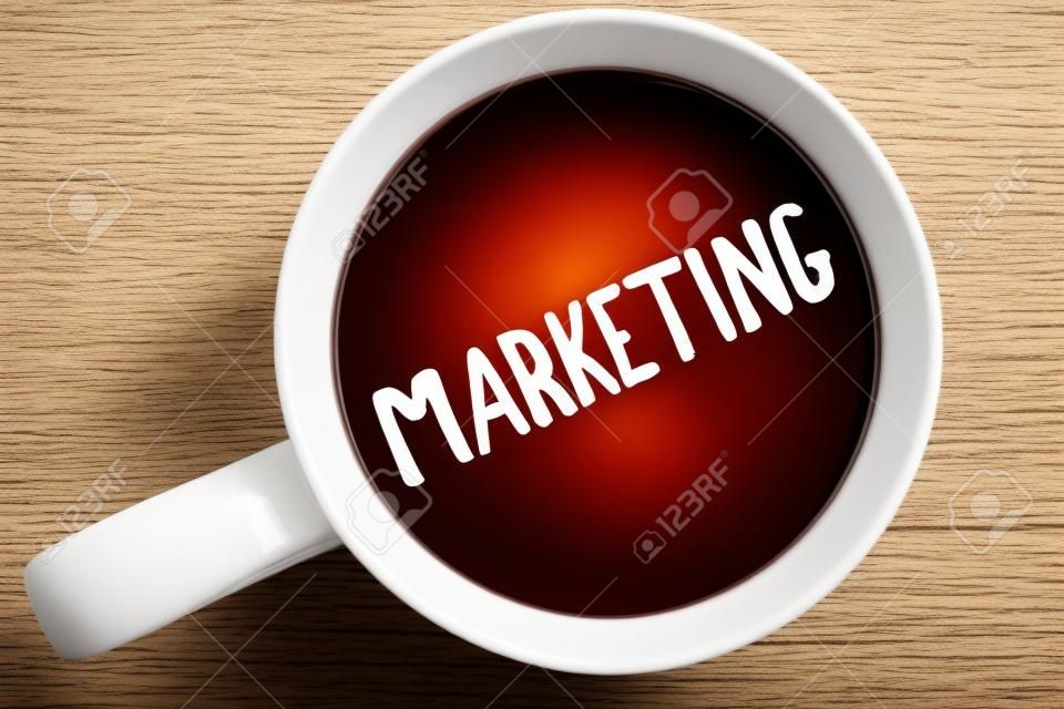 Handschrift Text schreiben Marketing. Konzept bedeutet Werbung für den Verkauf von Produkten einer Firma, um etwas geschriebenen Schwarzen Tee in weißem Cup einfarbigen Hintergrund zu fördern. Ansicht von oben.