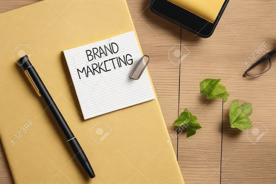 Writing note showing Brand Marketing. Business concept for Creating awareness about products around the world Wrinkle paper notebook and stationary placed on wooden background