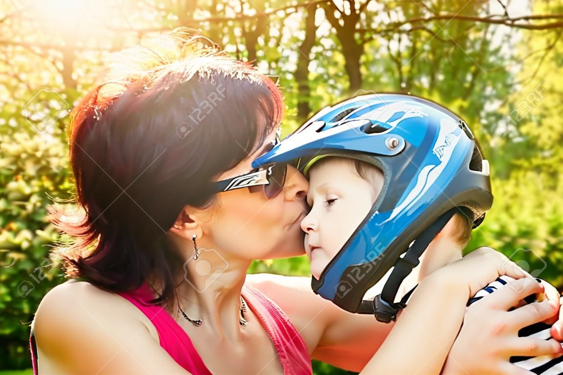 Matka całuje jej syna z rowerowego kasku na zewnątrz