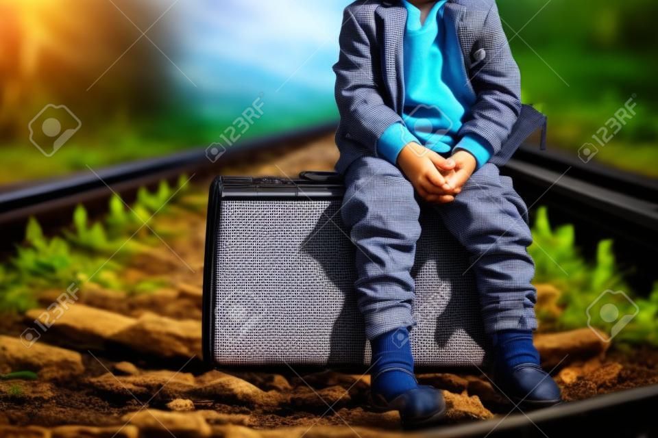 Little boy with suit case on railway out door. Travel concept