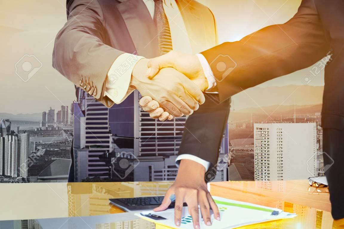 Double exposure of Great job,Sealing a deal,Successful business,Handshake,Businessman join together,Good agreement.two people shaking hands standing at the working place in city scape