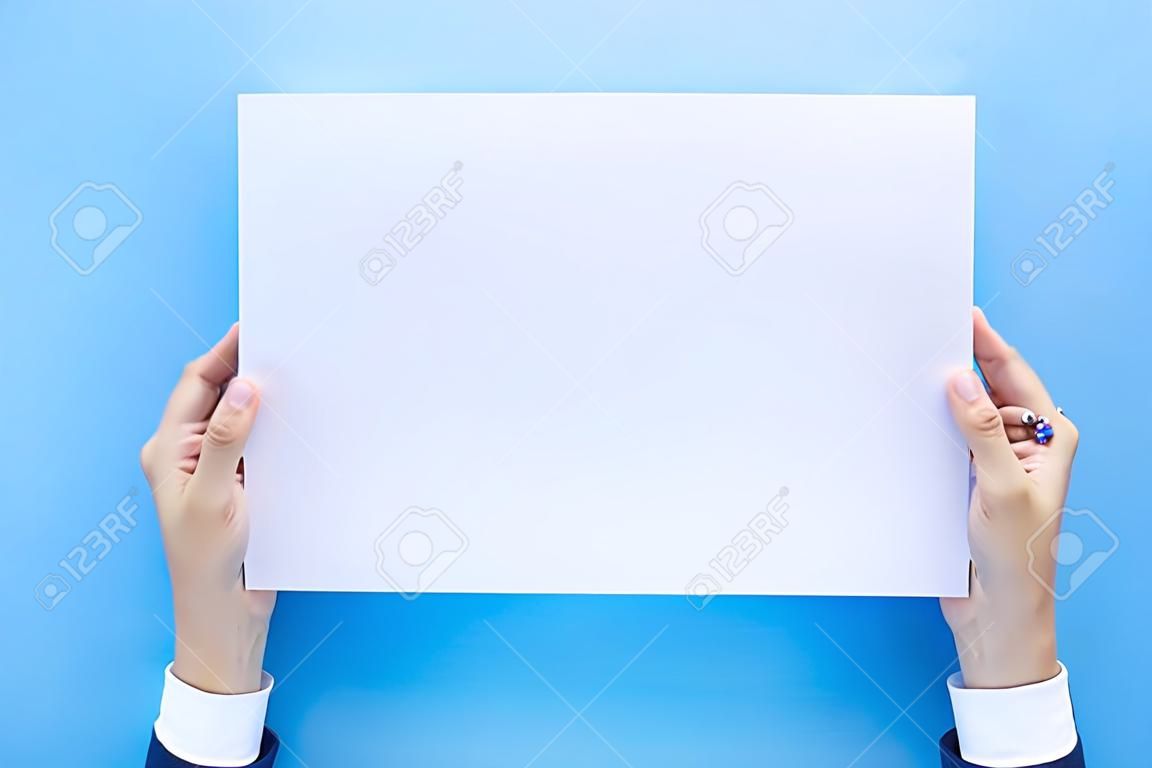 Schließen Sie die Hände, die leeres weißes leeres Briefpapier im A4-Format für Flyer oder Einladungsmock-up isoliert auf blauem Hintergrund halten.