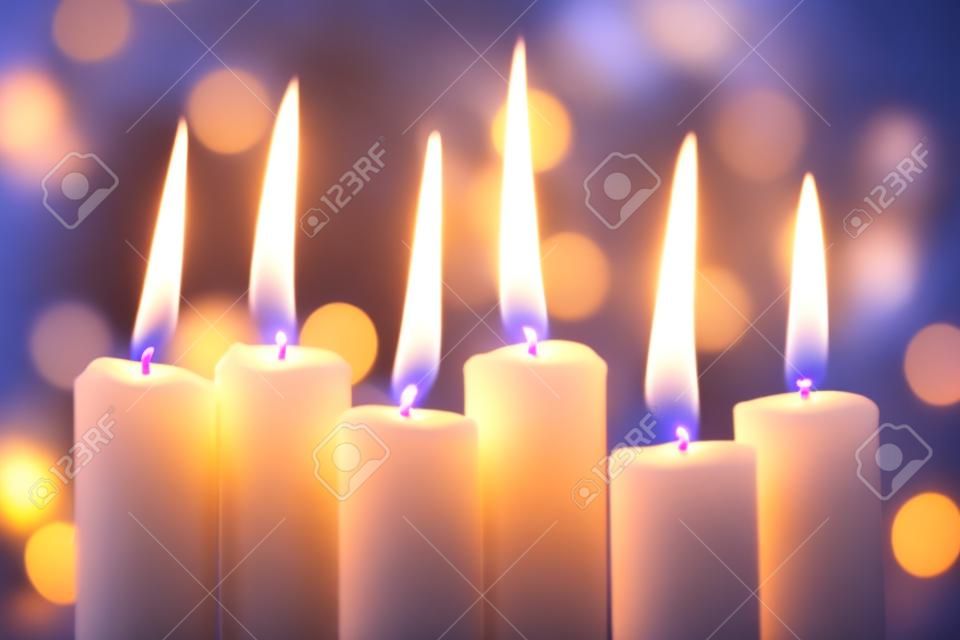Grupo de velas finas queimando e bokeh de luzes de Natal no fundo