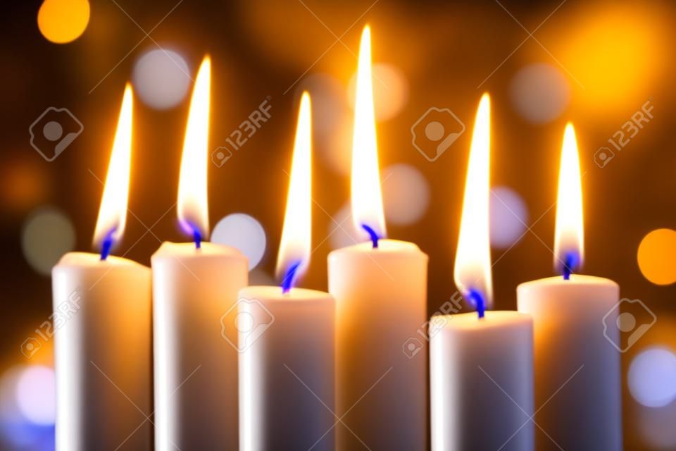 Grupo de velas finas queimando e bokeh de luzes de Natal no fundo