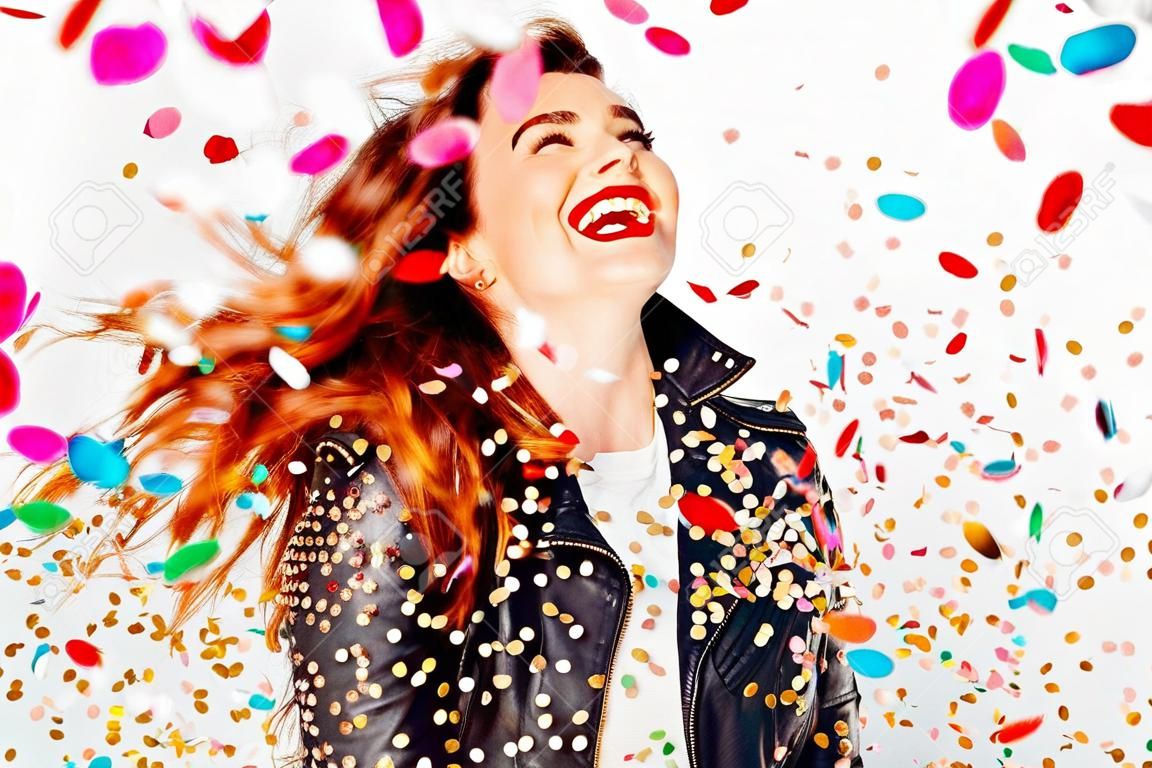Happy young and beatiful woman with fashion leather jacket enjoying the party with confetti