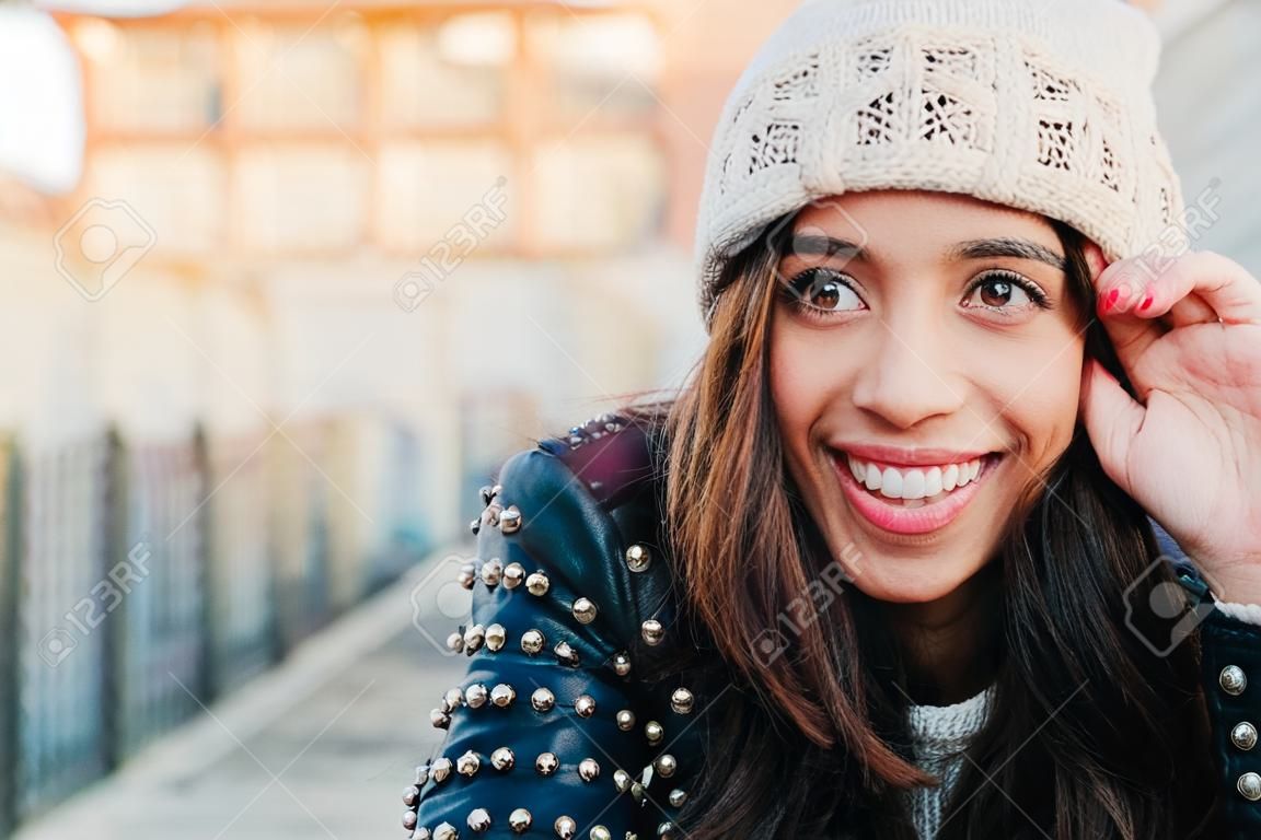 Portret szczęśliwej i pięknej młodej kobiety z uśmiechniętą wełnianą czapką i skórzaną kurtką