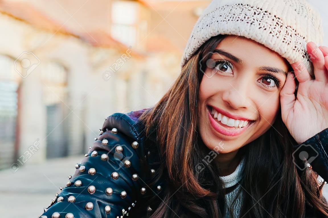 Ritratto di una giovane donna felice e bella con berretto di lana e giacca di lleather sorridente