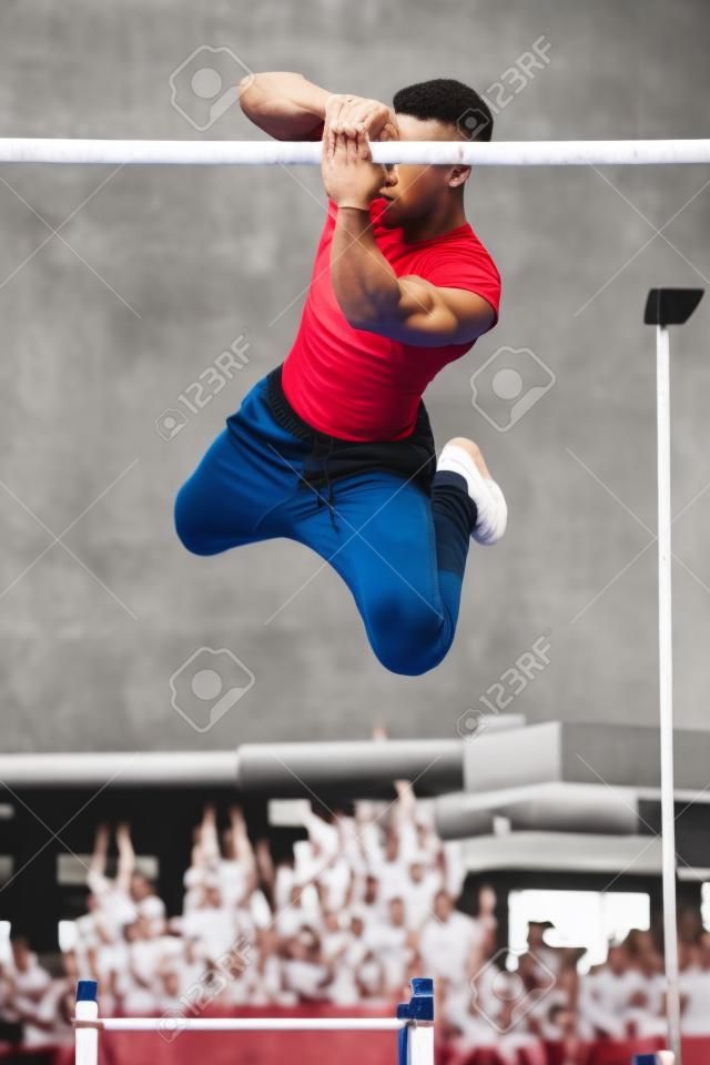 Junger athletischer Mann, der Gymnastik mit Drehungen an Stangen in einem Calisthenics-Fitnessstudio im Freien macht