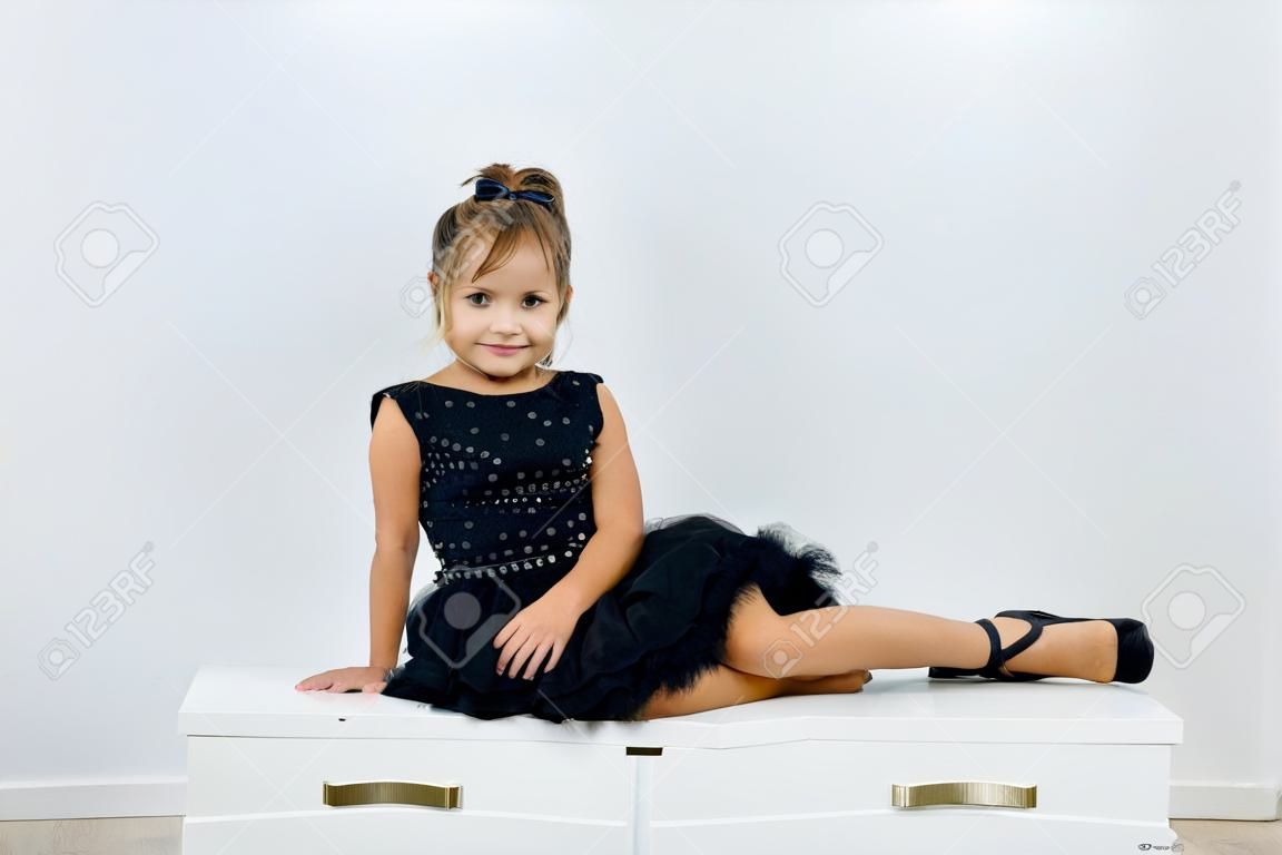 Une Petite Fille Mignonne Dans Une Robe Noire Est Assise Et Pose