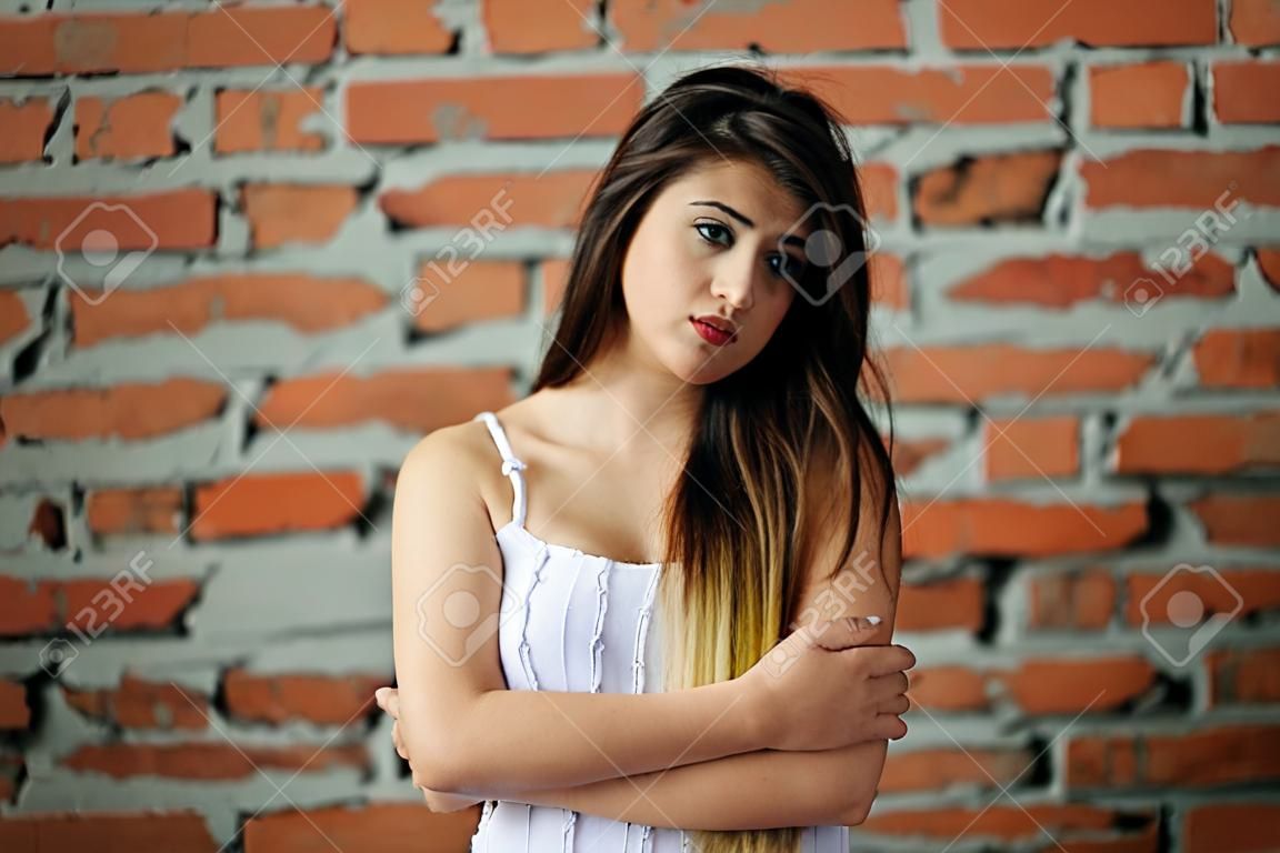 Portrait of young cute brunette girl background brick wall.