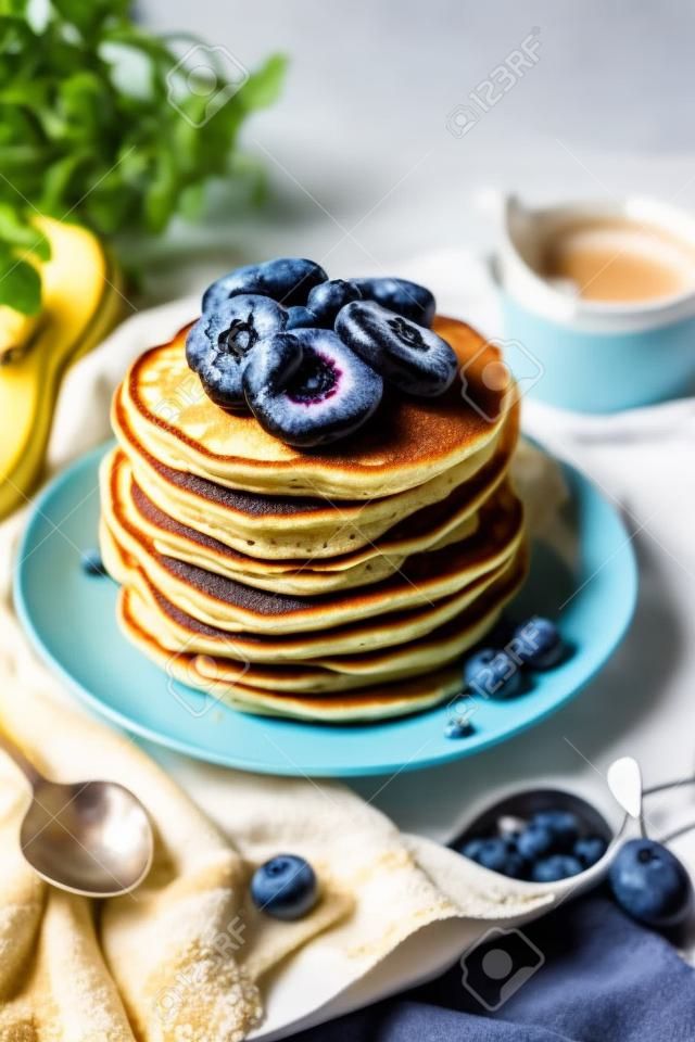 A stack of pancakes with fresh banana, blueberry and honey. Delicious homemade breakfast.