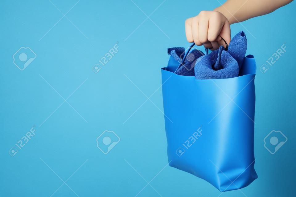 Hand holds bag with food on blue background