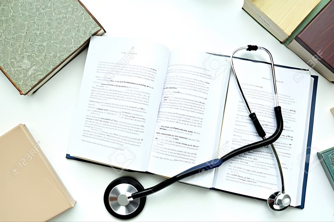 Books and stethoscope on white background, top view