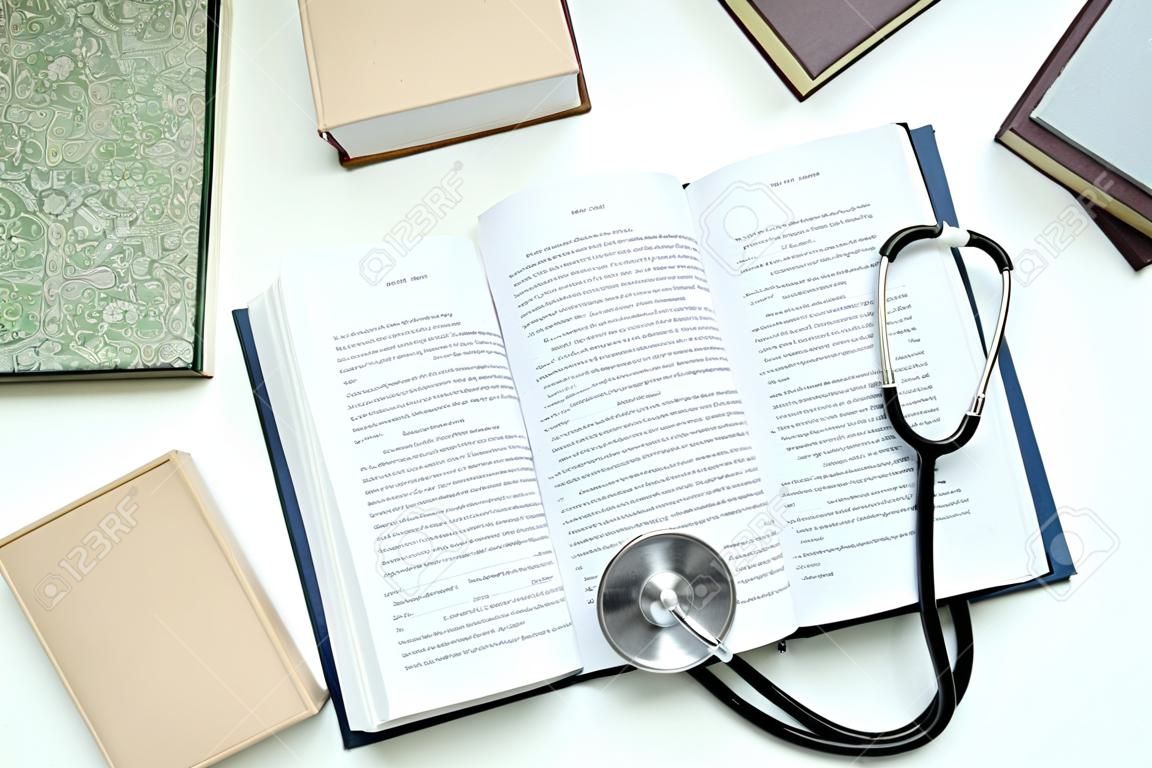 Books and stethoscope on white background, top view