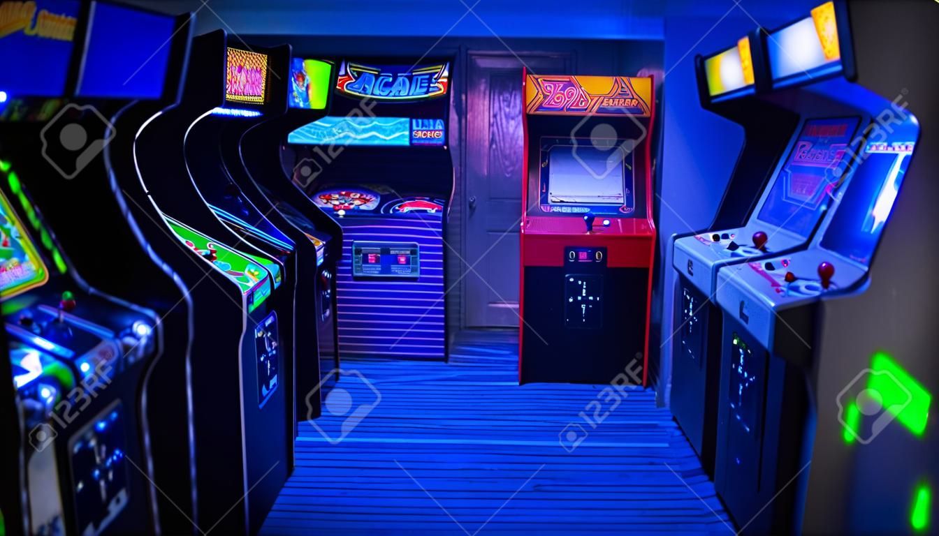 Old Vintage Arcade Video Games in an empty dark gaming room with blue light with glowing displays and beautiful retro design