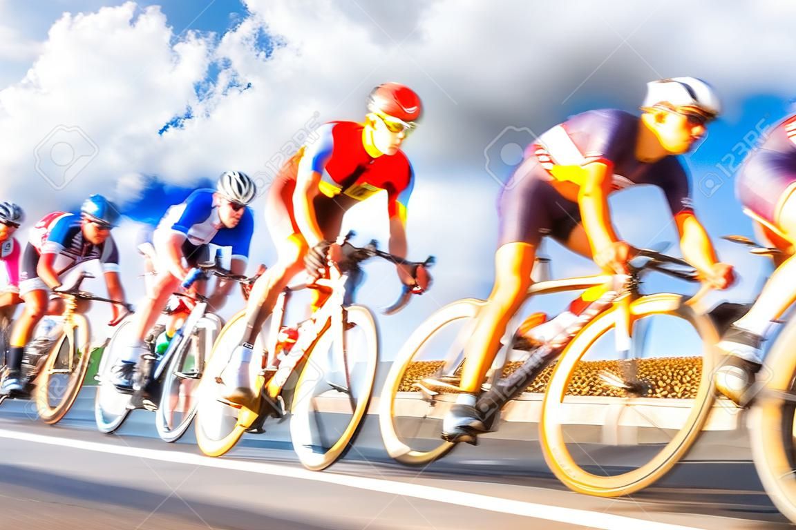 Grupa rowerzystów podczas wyścigu oświetlonego słońcem ruchu, rozmycie zachmurzonego nieba w tle
