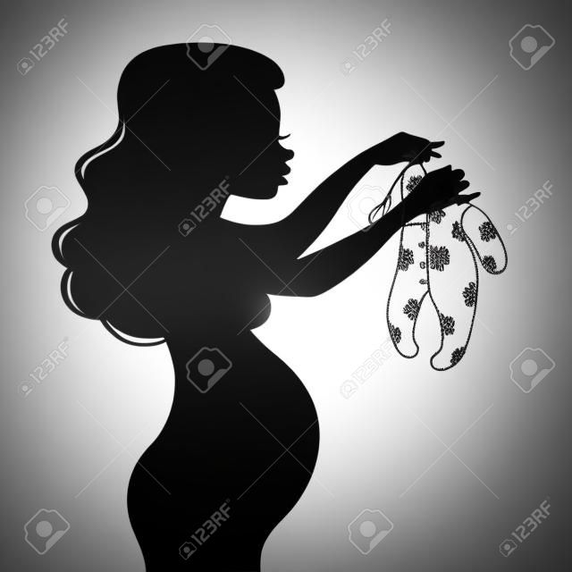 Sylwetka pięknej młodej kobiety w ciąży trzyma suwaki dzieci na białym tle