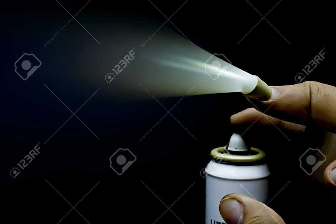 Close up view of a man spraying, A spray can in a hand on a black background Close-up