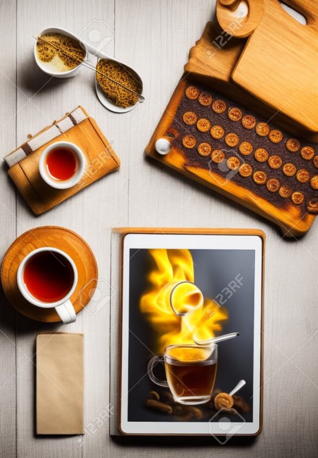 Food blog concept with cup of tea on tablet pc on wooden desk