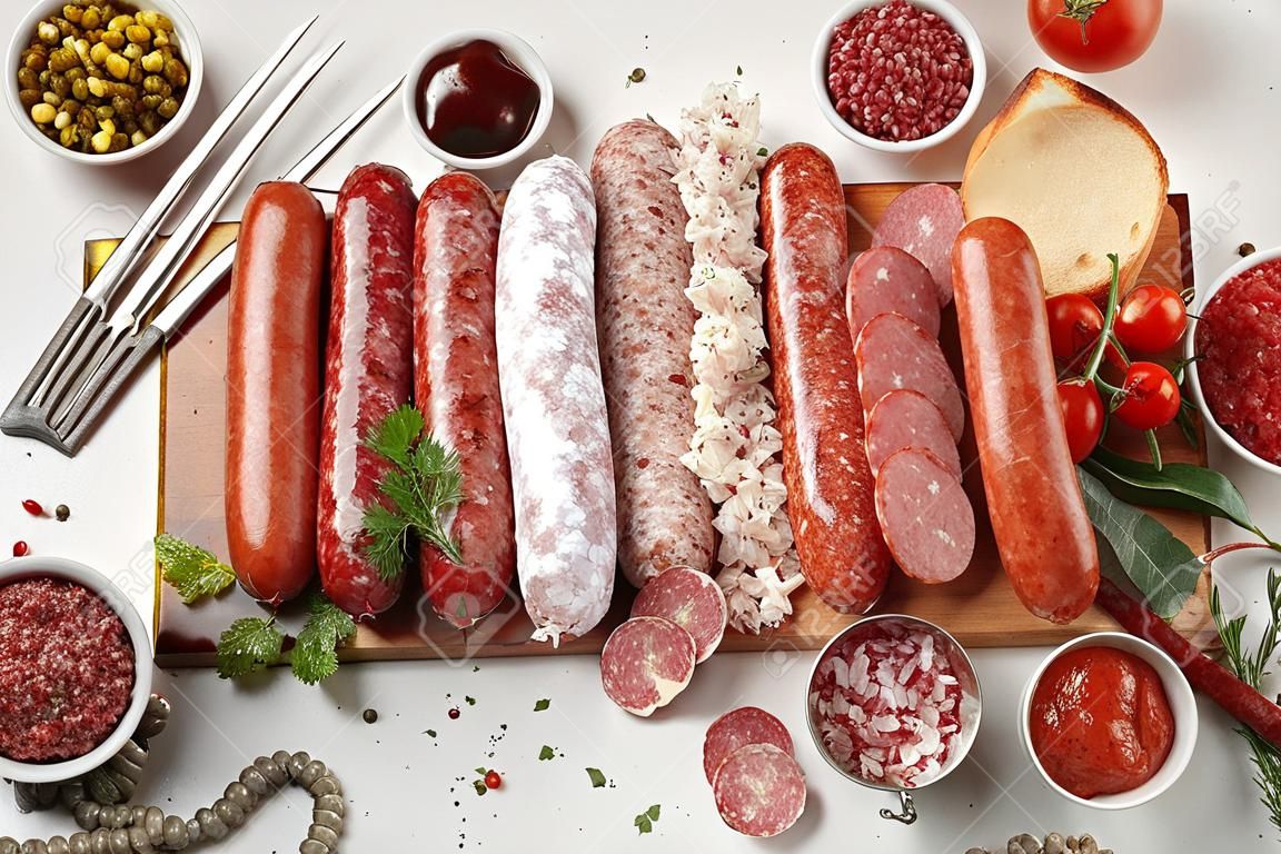 Sausages salami assortment on light background. Meat product made of finely chopped and seasoned meat.