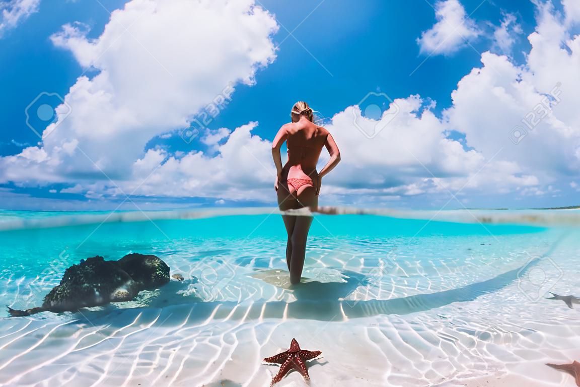 Hermosa mujer posando en el mar tropical con estrellas de mar, Islas Bahamas