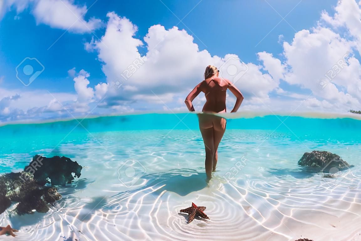 Piękna kobieta pozuje w tropikalnym morzu z rozgwiazdami, wyspy bahamy